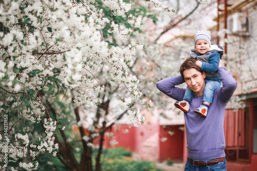 Happy father and son stand in the garden against the background of flowering trees