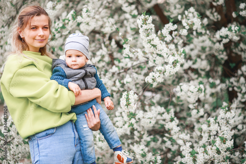 happy mother and son play against the background of a flowering tree. Spring, mother's day.