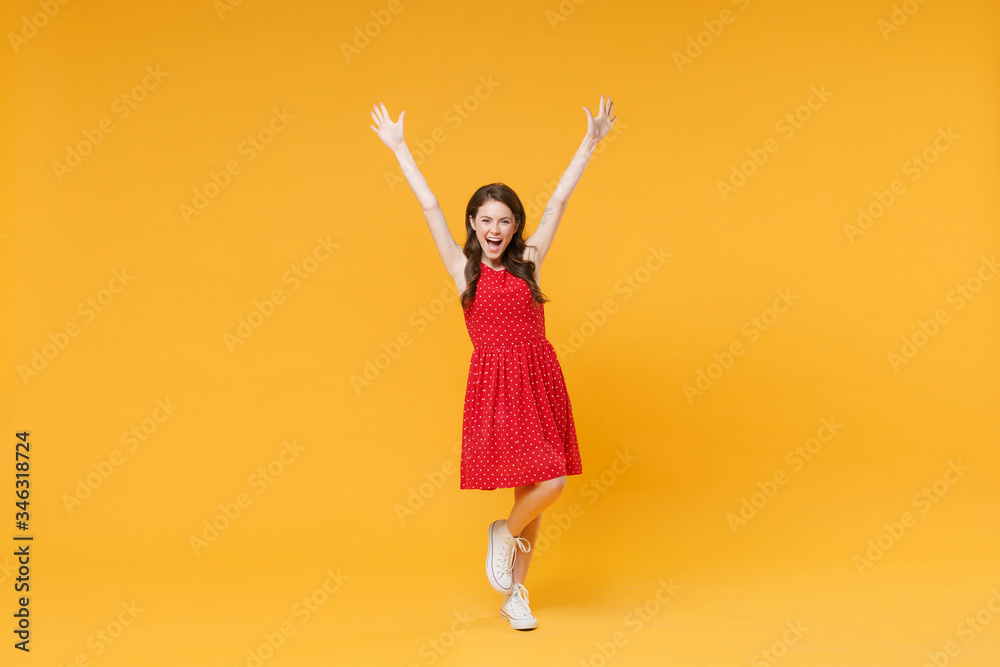 Excited young brunette woman girl in red summer dress posing isolated on yellow wall background studio portrait. People sincere emotions lifestyle concept. Mock up copy space. Rising spreading hands. Excited young brunette woman girl in red summer dress posing isolated on yellow wall background studio portrait. People sincere emotions lifestyle concept. Mock up copy space. Rising spreading hands.