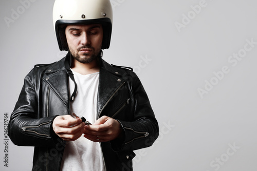 Shot of bearded biker man wearing retro white helmet and holding motorcycle keys. Free space for text.