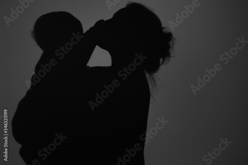 Silhouette Of Happy Mother and Baby. Mom kissing baby, Happy Mother's Day concept