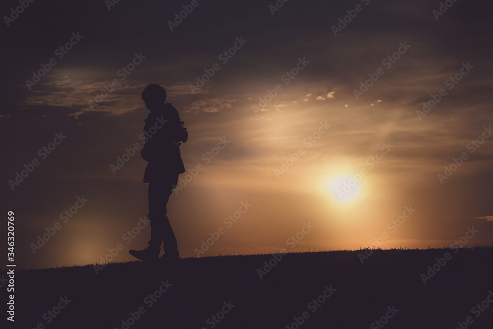 夕暮れの丘に立つ男性のシルエット