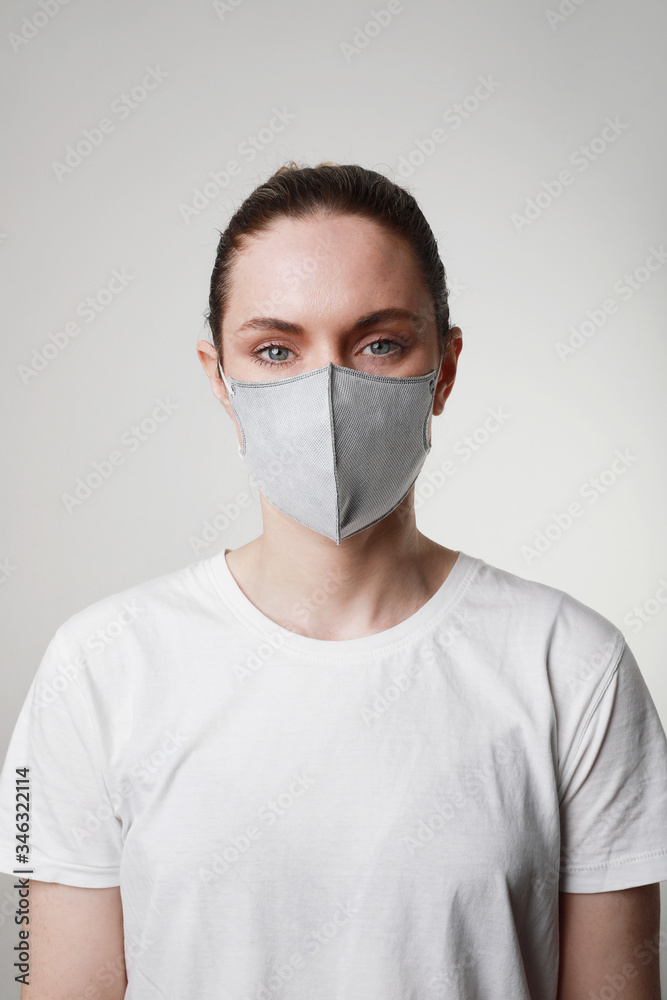 Vertical portrait of young woman in medical face protection mask indoors on white background. Protection of the virus. Vertical portrait of young woman in medical face protection mask indoors on white background. Protection of the virus.