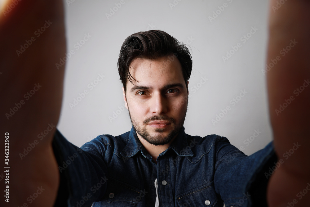 Obraz premium Bearded man in the denim outfit which mixed with bright white t-shirt posing over white wall. Space for text.