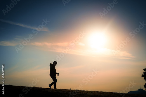 夕暮れの丘に立つ男性のシルエット © kanzilyou