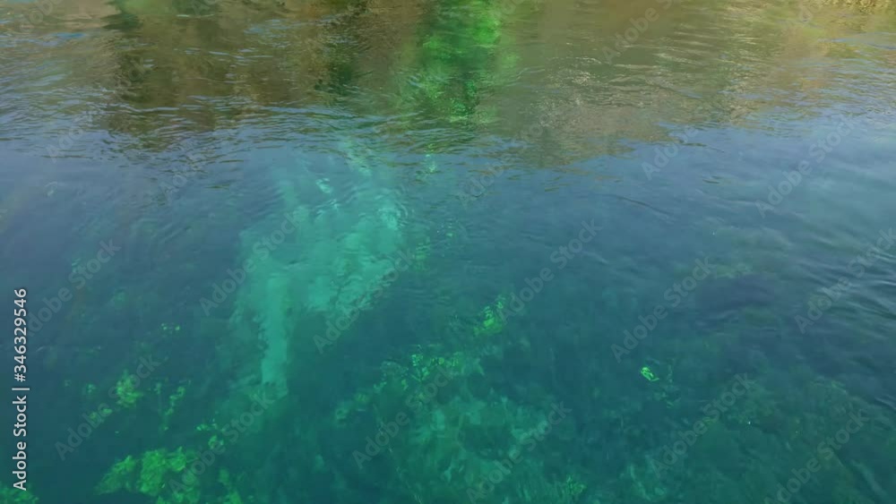 Looking down into the weed and sand of the flowing turquoise and green hypnotic waters of Azmak river in Akyaka, Gokova plain, Mugla, Turkey Looking down into the weed and sand of the flowing turquoise and green hypnotic waters of Azmak river in Akyaka, Gokova plain, Mugla, Turkey