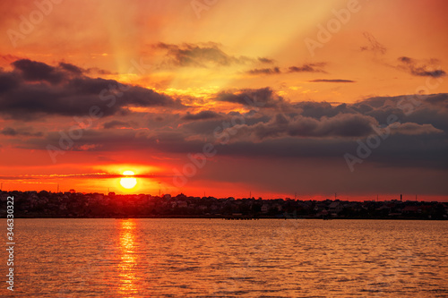 Beautiful sunrise on the lake, with the reflection of the sun on the water and the rays of the sun passing through the clouds