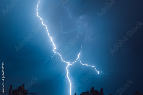 A strong flash of lightning in the sky while a strong storm hits the sky.