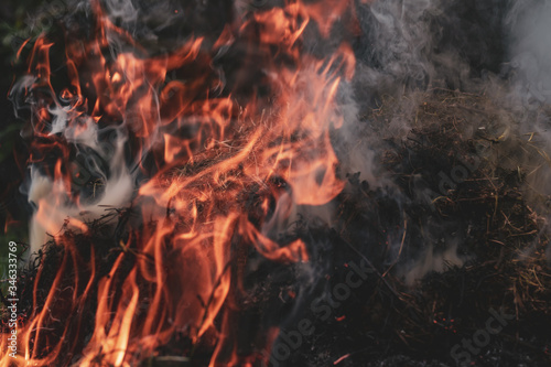 dark colors image of fire and smoke of burning grass on a countryside field