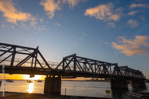 Sun rises on horizon under Tauraga railway bridge.
