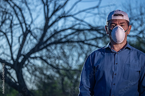 Middle-aged man dressed in blue shirt puzzled by coronavirus situation in parke looking thoughtful