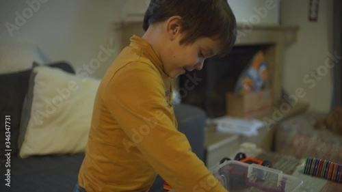 Caucasian toddler boy, plays with plastic magnetic toy at home, side view, medium shot photo