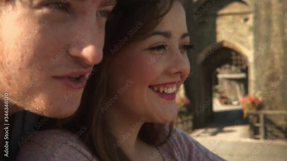 Happy cheerful romantic young couple hugging enjoying each others company smiling looking out to the distance on warm summer day extreme closeup slow motion