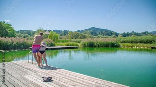 Millennial fun couple take off clothes and run before jumping into lake photo
