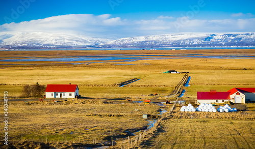 Icelalndic farm houses and barns with bright red roofs and snow capped mountains photo