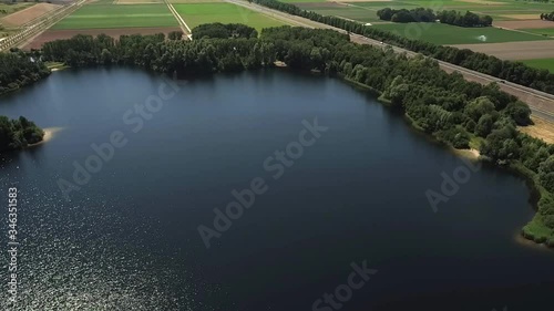 Aerial wide shot above a lake that is created due to sand mining for construction of the highway in the clip photo