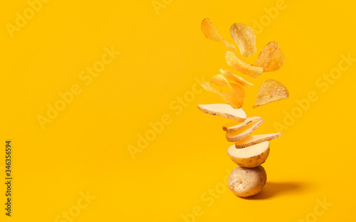 Flying potato slice into potato chips isolated on yellow background