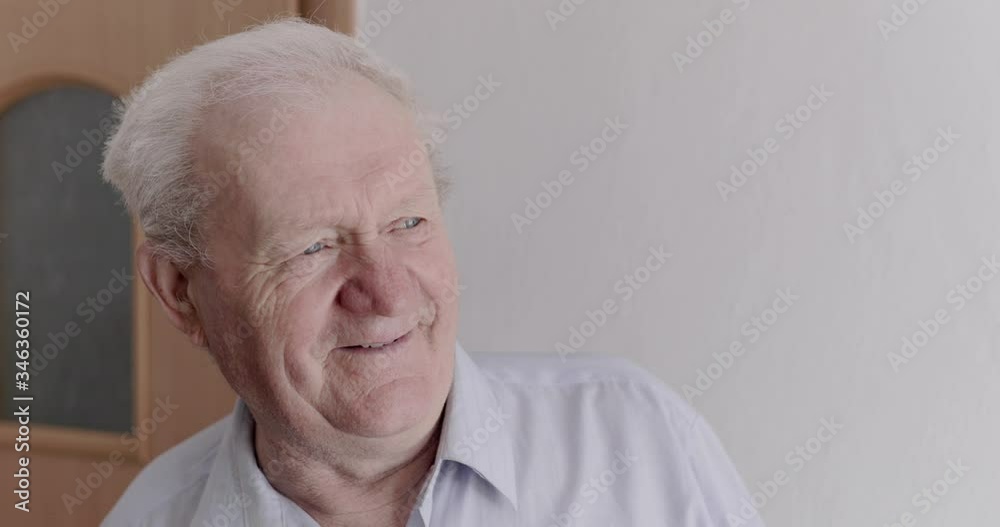 Joyful senior man waving hand to and calling somebody, then smiling in home Joyful senior man waving hand to and calling somebody, then smiling in home