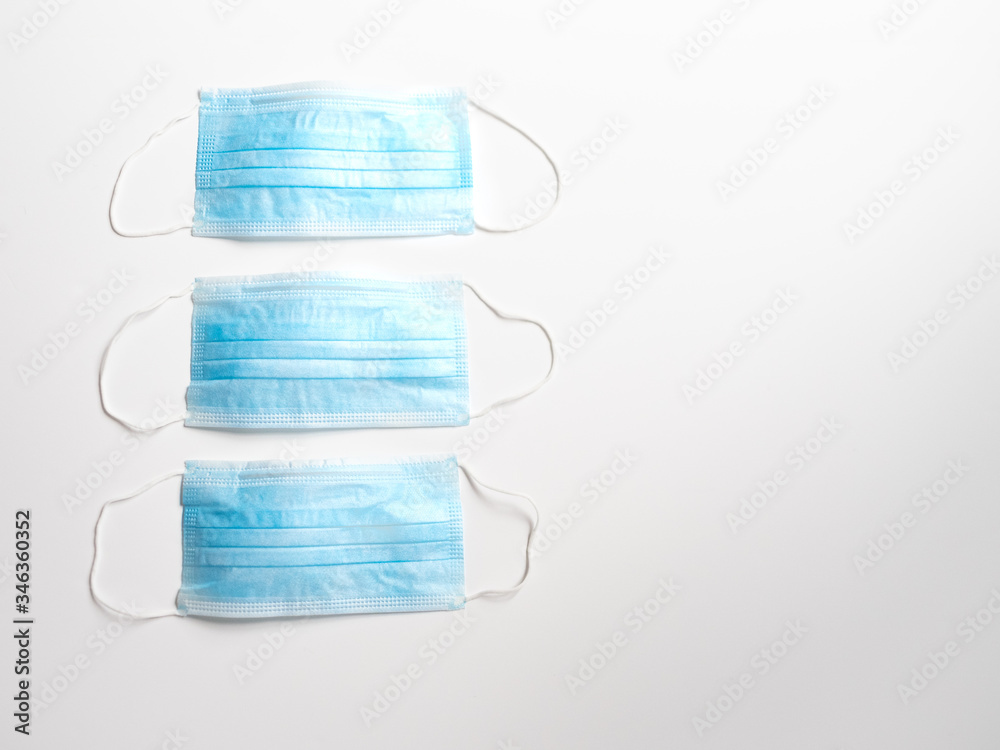 Φωτογραφία Row of Three Light Blue Disposable Face Masks photographed with a shallow depth of field on a white background