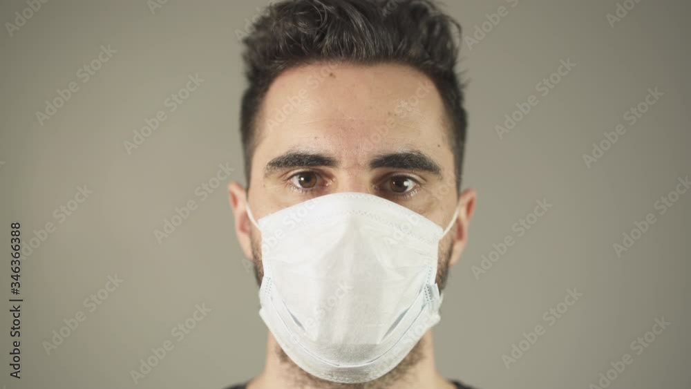 Close-up of Isolated man with surgical Mask, brown hair and eyes, facing at camera in studio, during covid-19 pandemic virus in France. 4K UHD. One person young man. Prevention. Close-up of Isolated man with surgical Mask, brown hair and eyes, facing at camera in studio, during covid-19 pandemic virus in France. 4K UHD. One person young man. Prevention.