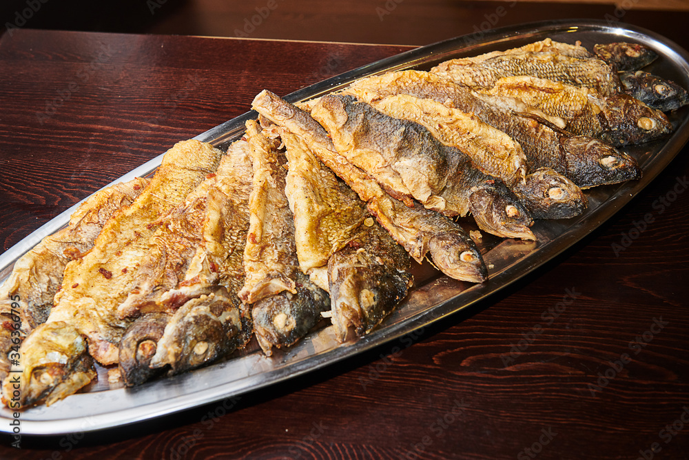 Fried grayling on a tray on a dark background