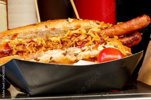 Sausage hot dog during fast food festival event. Outside catering or outdoor party grab and go dish