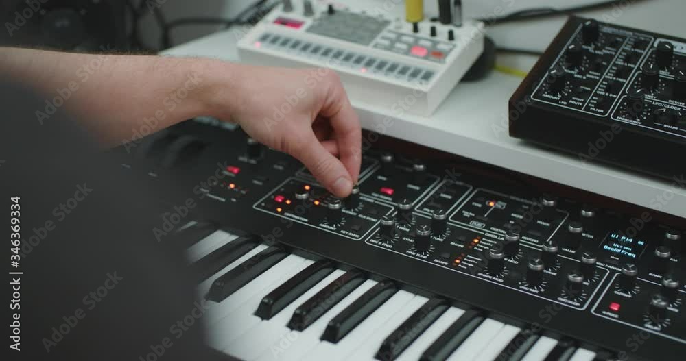 A man tweaking a synthesizer