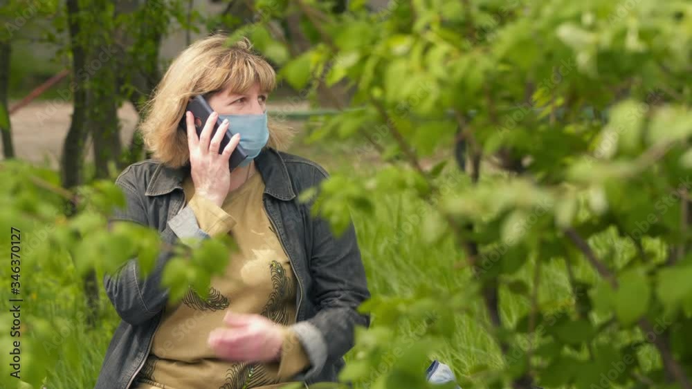 A young woman in a medical mask is talking on the phone.. The concept health and safety, COVID 19 coronavirus quarantine, virus protection A young woman in a medical mask is talking on the phone.. The concept health and safety, COVID 19 coronavirus quarantine, virus protection