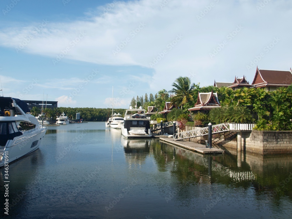 Luxury yachts and buildings. Narrow forwarding. Asian-style villas with Chinese roofs and private yacht moorings. Expensive yacht's club. Luxury and wealth on a paradise tropical island. Phuket Marina