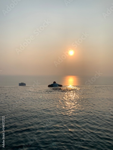 Sihouette of blurry man at the edge of infinity swimming pool overlooking ocean at sunset © Veruree