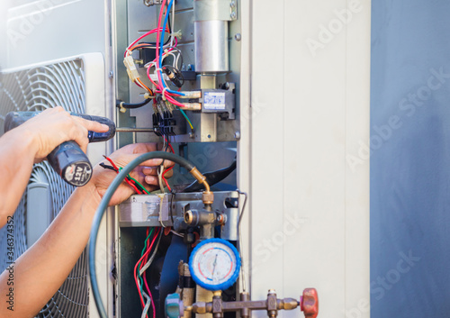 Fotografia, Obraz Male technician hands using a screwdriver fixing modern air conditioner, repairi