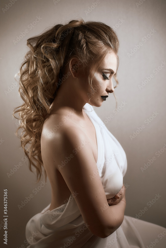 tanned girl with black lips and arrows with light curly hair and professional bright makeup, isolates on white in a silk white dress tanned girl with black lips and arrows with light curly hair and professional bright makeup, isolates on white in a silk white dress