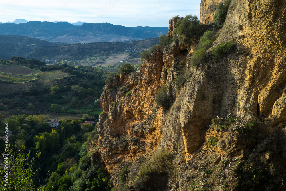View of the beautiful cliffs and the valley from the old white town of Ronda in Andalusia, Spain. The picture was taken at sunset time