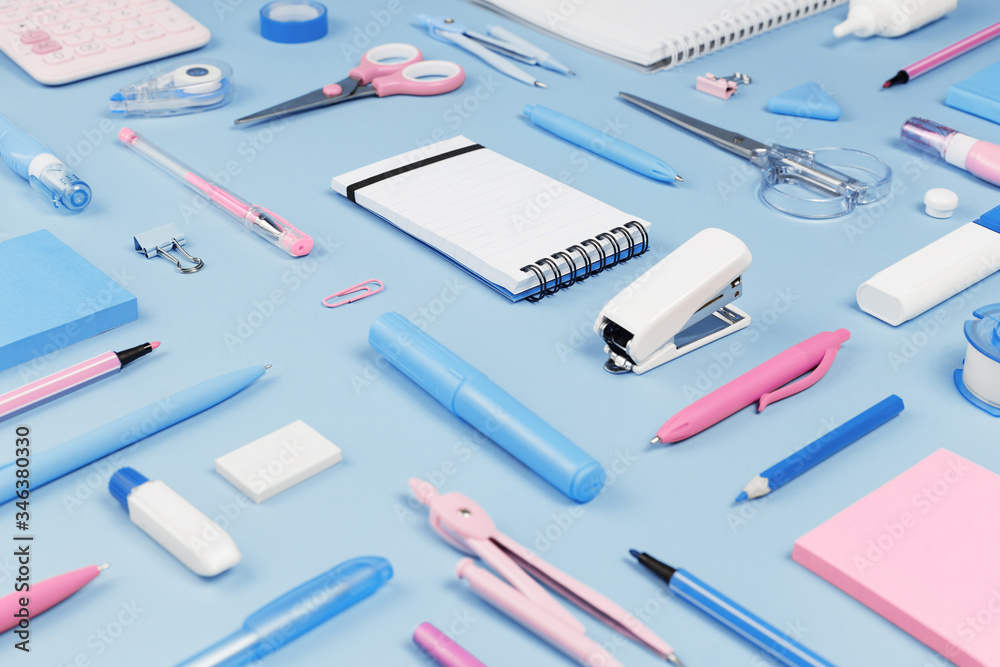 Assorted office and school pink white and blue stationery on pastel background as border. Top view with copy space. back to school or education and craft concept. Blue monochrome. Notepad Assorted office and school pink white and blue stationery on pastel background as border. Top view with copy space. back to school or education and craft concept. Blue monochrome. Notepad