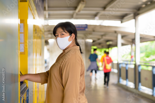 Overweight Asian woman with mask using self service locker box