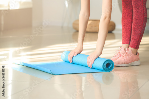 Sporty young woman with yoga mat at home © Pixel-Shot