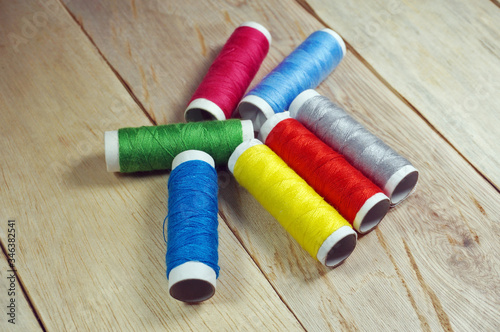 Top view colorful spools of thread on wooden table        