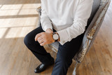 Close up of the man in white shirt and black pants adjusting watches, time is money concept, concept of waiting