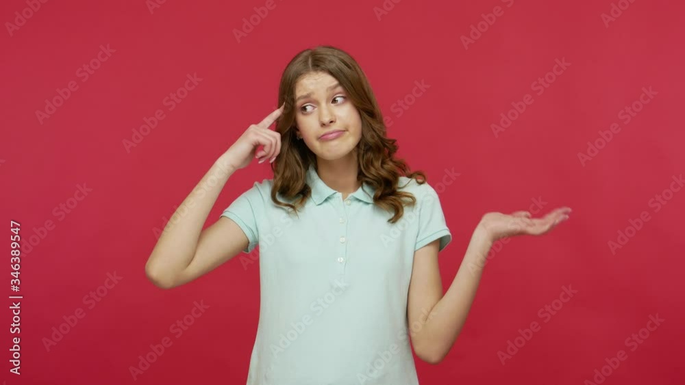 Silly idea! Upset frustrated woman in polo t-shirt making stupid gesture with finger near head, dumb insane mind, looking with displeased unhappy expression. studio shot isolated on red background Silly idea! Upset frustrated woman in polo t-shirt making stupid gesture with finger near head, dumb insane mind, looking with displeased unhappy expression. studio shot isolated on red background