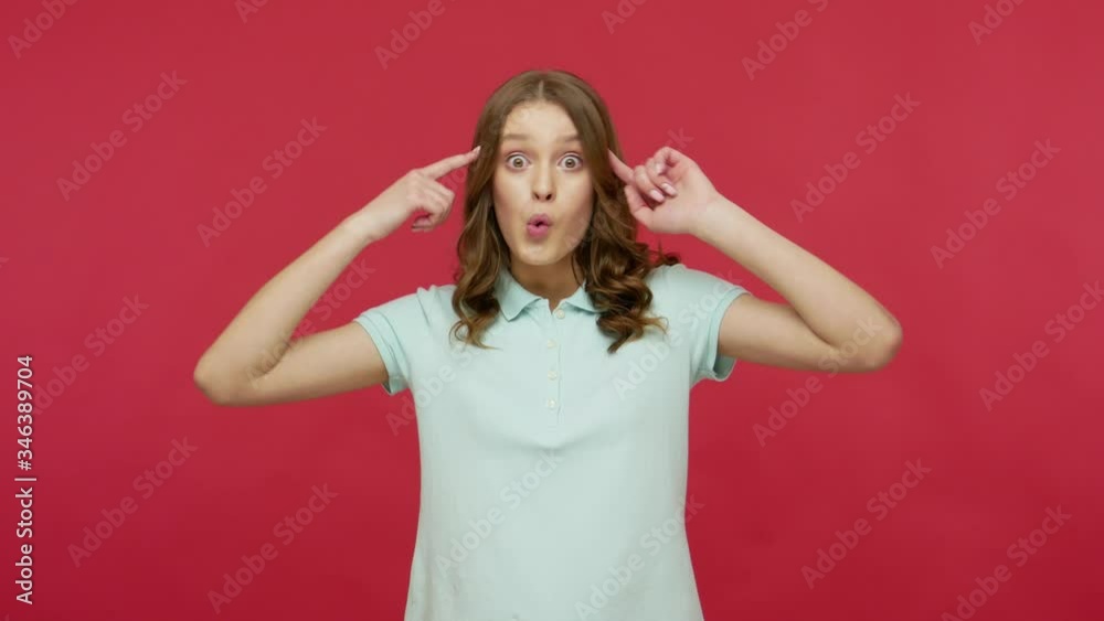You are crazy, out of mind! Young brunette woman in polo t-shirt making stupid gesture with finger near head, looking annoyed and blaming for insane idea. indoor studio shot isolated on red background You are crazy, out of mind! Young brunette woman in polo t-shirt making stupid gesture with finger near head, looking annoyed and blaming for insane idea. indoor studio shot isolated on red background