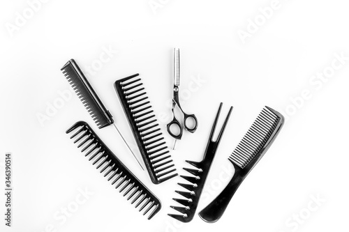 Combs, hairbrush, scissors - hairdresser eqiupment - on white table top-down