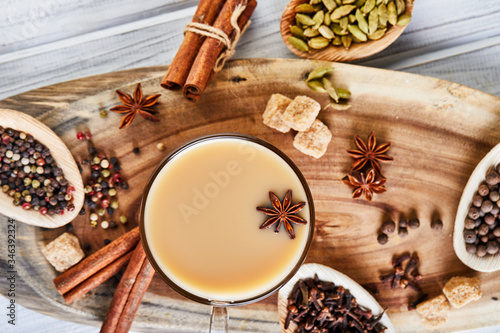 Traditional Indian drink - masala tea with spices. Cinnamon, cardamom, anise, sugar, cloves, pepper on a light wooden background.