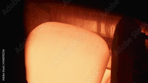 The red-hot sheet of metal rotates on the conveyor. Slow motions.