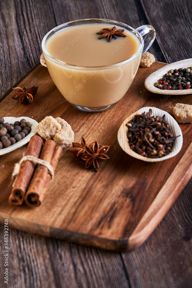 Traditional Indian drink - masala tea with spices. Cinnamon, cardamom, anise, sugar, cloves, pepper on a dark wooden background. Traditional Indian drink - masala tea with spices. Cinnamon, cardamom, anise, sugar, cloves, pepper on a dark wooden background.