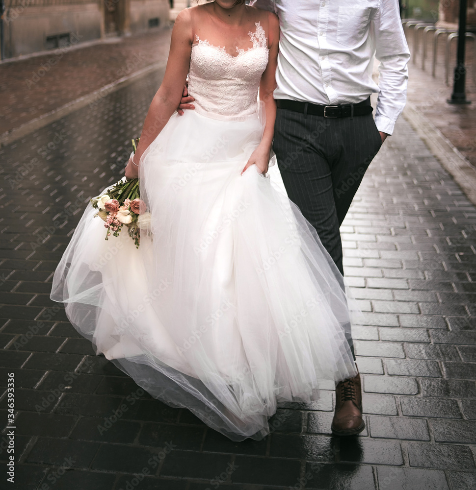 Bride and groom walking on the Old European Town streets. Marriage in Europe. Walking on pavement after the rain