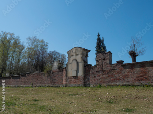 old red brick wall of country cemetery at village Cvikov in luzicke hory, Lusatian Mountains, early spring, blue sky