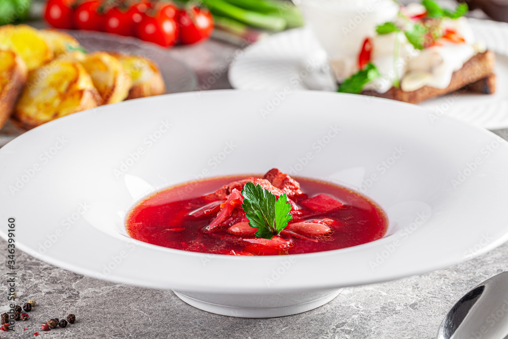 Modern Ukrainian cuisine in European style. Borsch soup with meat and sour cream. Beautiful serving dish in a restaurant in a white plate. background image, copy space text