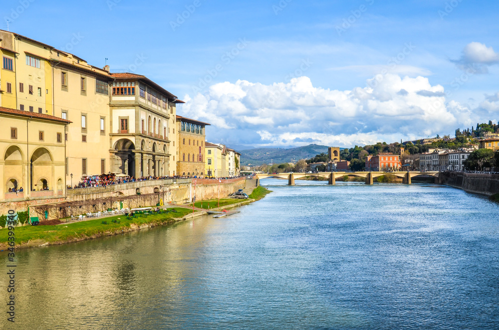 Cityscape of beautiful Florence, Tuscany, Italy photographed from the famous Ponte Vecchio Bridge. Historical buildings including Galleria degli Uffizi along the Arno river. Horizontal photo.