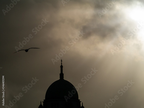 Silhouette of dome of Galway Cathedral , dramatic cloudy sky in the background with light rays bursting through the clouds.