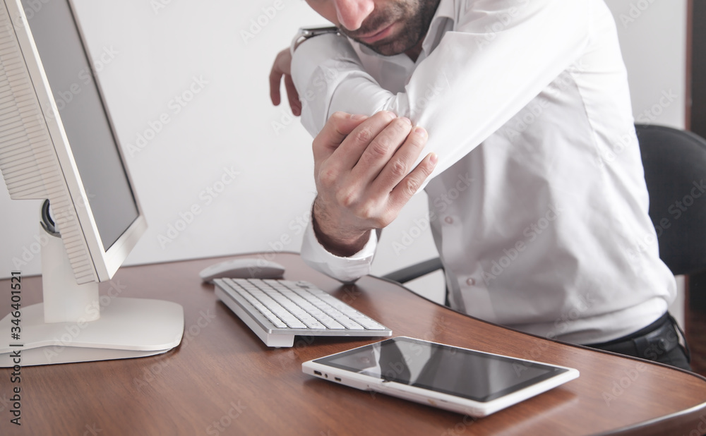Businessman suffering from elbow pain in office.
